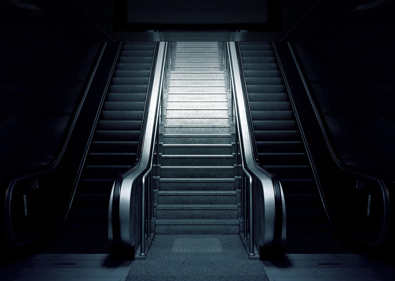 The stairs down. The only sign is a hand-painted arrow and a strip of green light.